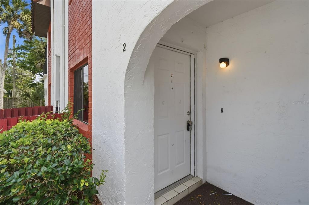 The exterior view shows a white front door with the number two under an archway — 910 BIG TREE ROAD UNIT 202, SOUTH DAYTONA, FL