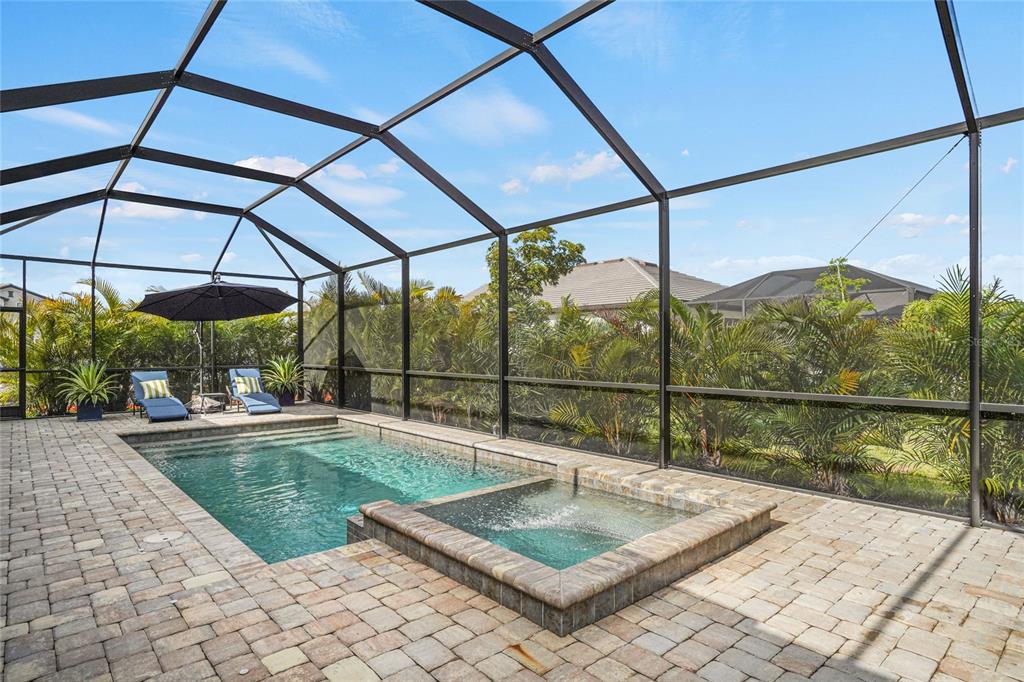 A screened-in patio features a rectangular swimming pool, an attached spa, and paver decking — 4970 OYSTER PEARL STREET, LAKEWOOD RANCH, FL