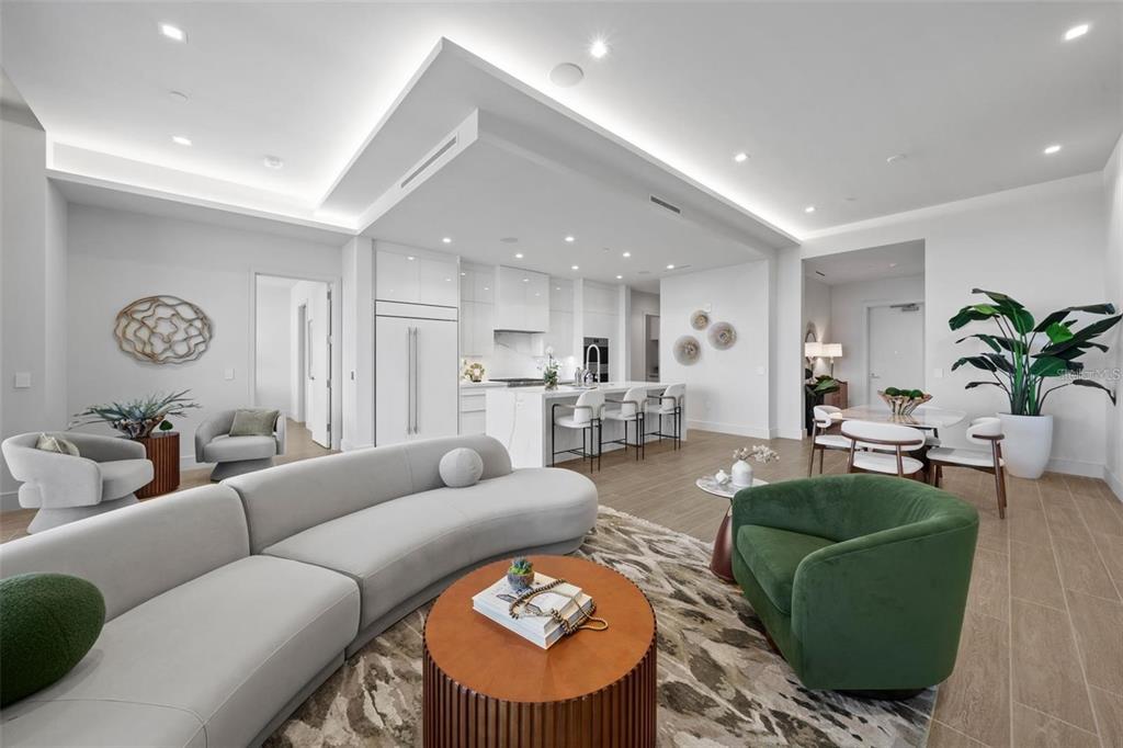 A modern open-concept living room and kitchen featuring white cabinetry, a curved sofa, and tile flooring — 1591 GULF OF MEXICO DRIVE UNIT 515, LONGBOAT KEY, FL