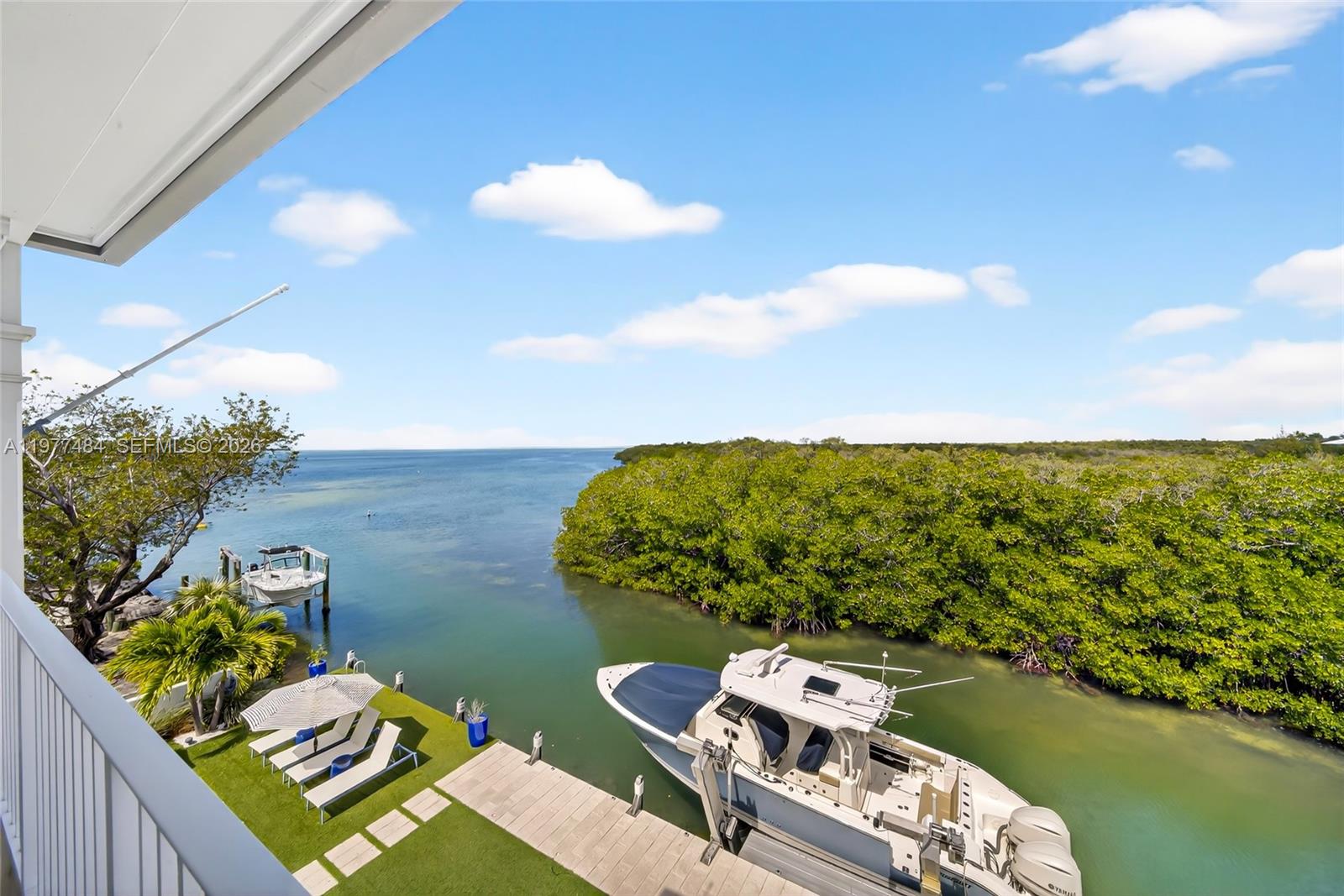 An elevated view shows a boat docked at a pier next to a grassy yard — 146 Mockingbird Rd, Tavernier FL 33070, TAVERNIER, FL