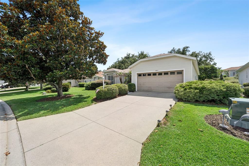 A single-story house with a beige garage and a concrete driveway sits on a lawn — 5000 SAWGRASS LAKE CIRCLE, LEESBURG, FL