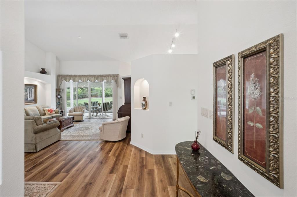 A foyer with a marble console table leads into a living room with wood flooring — 5000 SAWGRASS LAKE CIRCLE, LEESBURG, FL