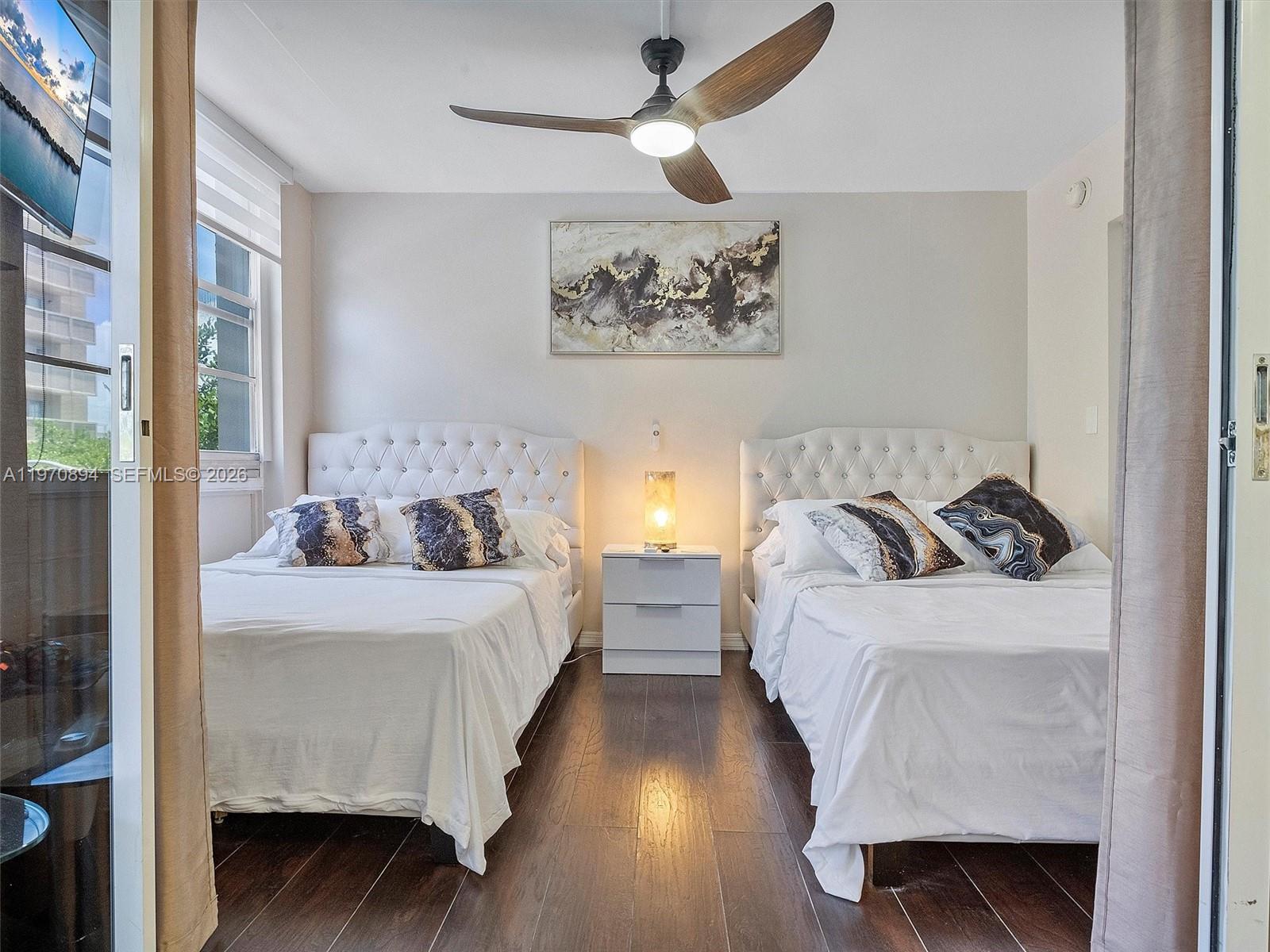 A bedroom features two beds with white tufted headboards, a central nightstand, and a ceiling fan — 710 Washington Ave, Miami Beach FL 33139, MIAMI BEACH, FL