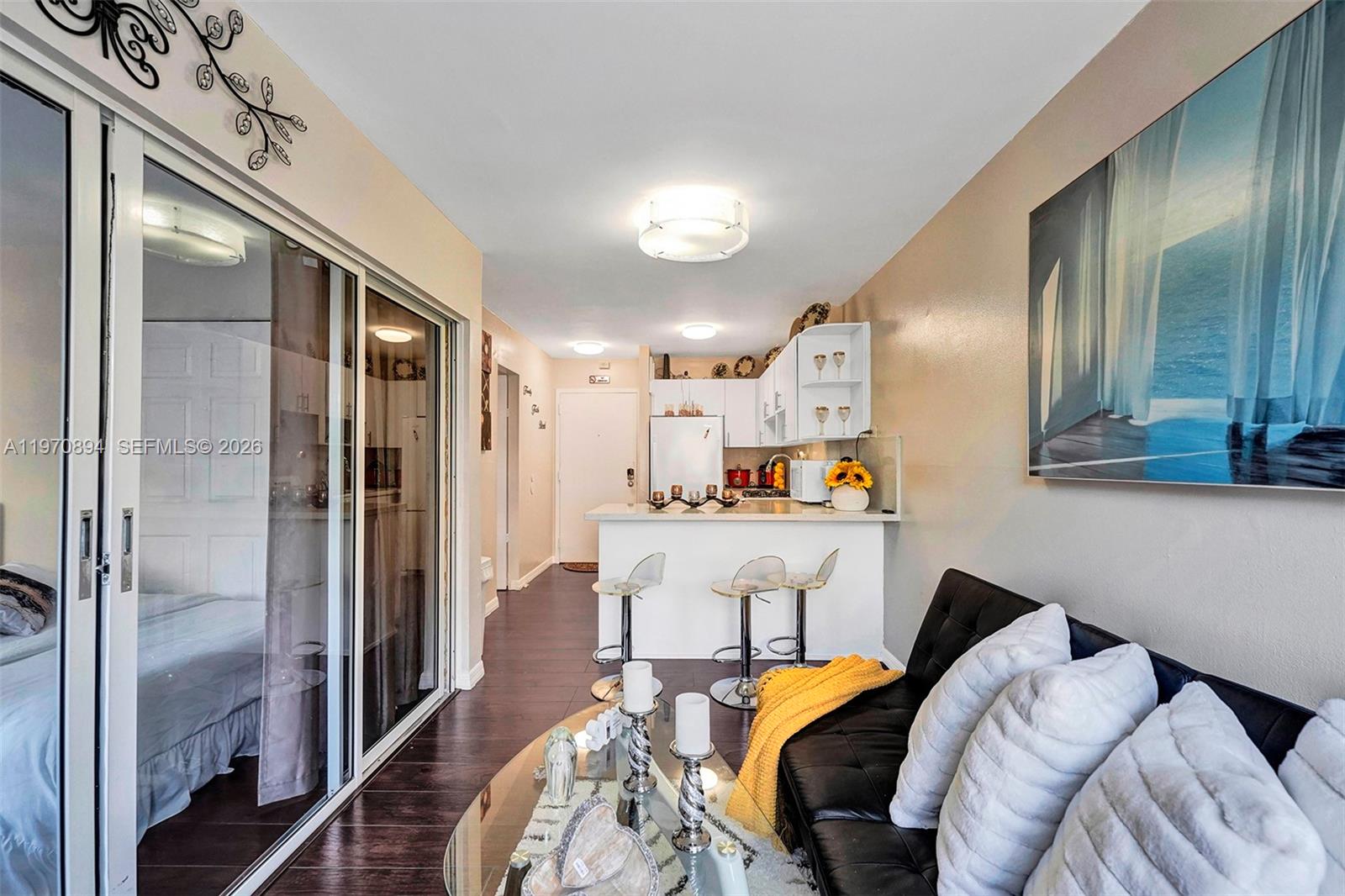 A living room features a black sofa, glass coffee table, and an open kitchen area — 710 Washington Ave, Miami Beach FL 33139, MIAMI BEACH, FL