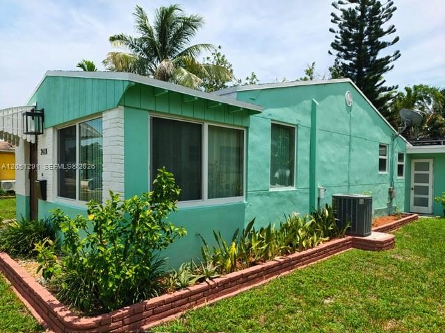 A light green house with a brick planter box and a palm tree in the background — 2418 Scott St, Hollywood FL 33020, HOLLYWOOD, FL