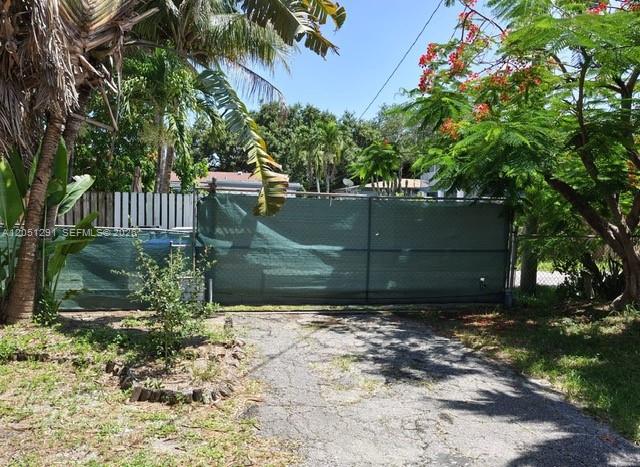 A green privacy screen covers a metal gate at the end of a paved driveway — 2418 Scott St, Hollywood FL 33020, HOLLYWOOD, FL