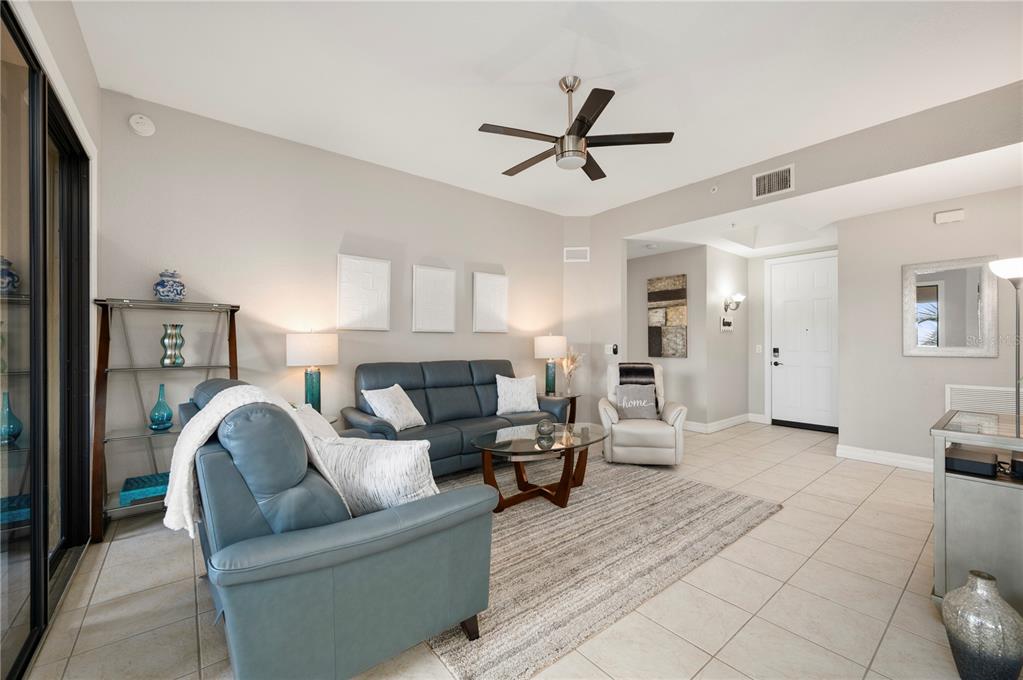A living room features blue leather furniture, a glass coffee table, and a ceiling fan — 98 VIVANTE BOULEVARD UNIT 9844, PUNTA GORDA, FL