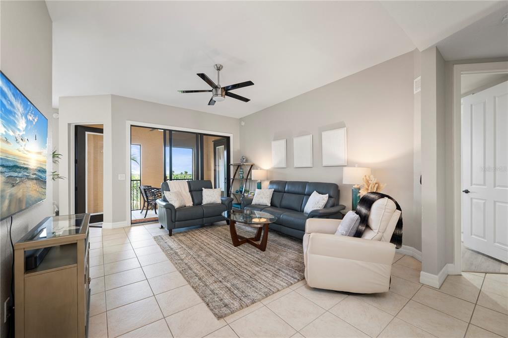 A living room features tile floors, a ceiling fan, leather furniture, and a sliding glass door — 98 VIVANTE BOULEVARD UNIT 9844, PUNTA GORDA, FL
