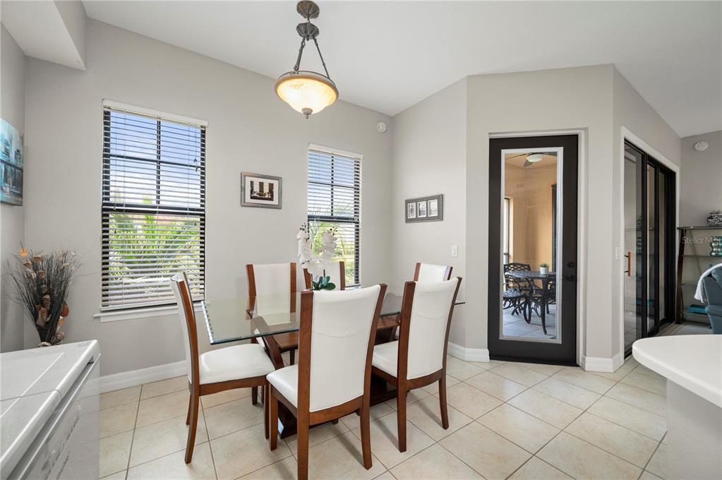 A dining area with a glass-top table, four chairs, tile flooring, and a glass door — 98 VIVANTE BOULEVARD UNIT 9844, PUNTA GORDA, FL