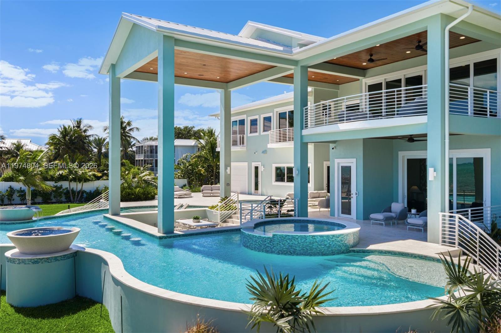 A multi-story light blue house features a large swimming pool with a built-in hot tub — 88351 Old Hwy, Islamorada FL 33070, ISLAMORADA, FL