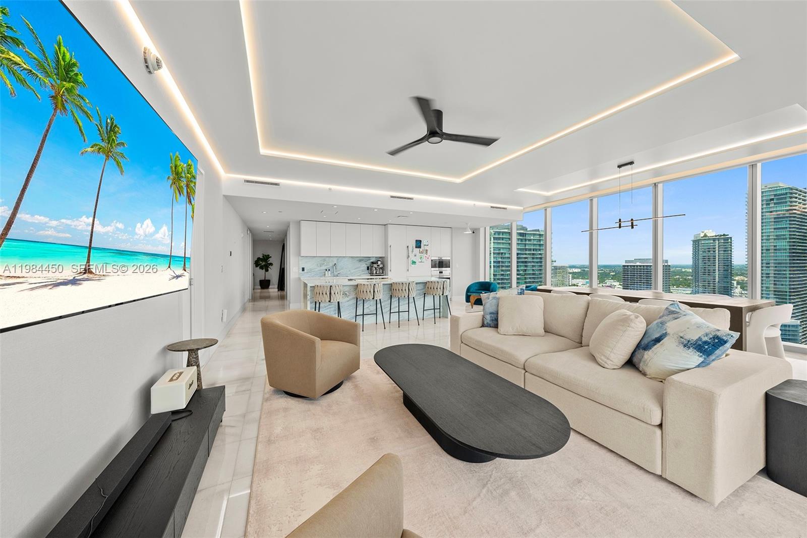 A modern living room features a large television, a beige sofa, and floor-to-ceiling windows — 700 NE 26th Ter # 3401, Miami FL 33137, MIAMI, FL