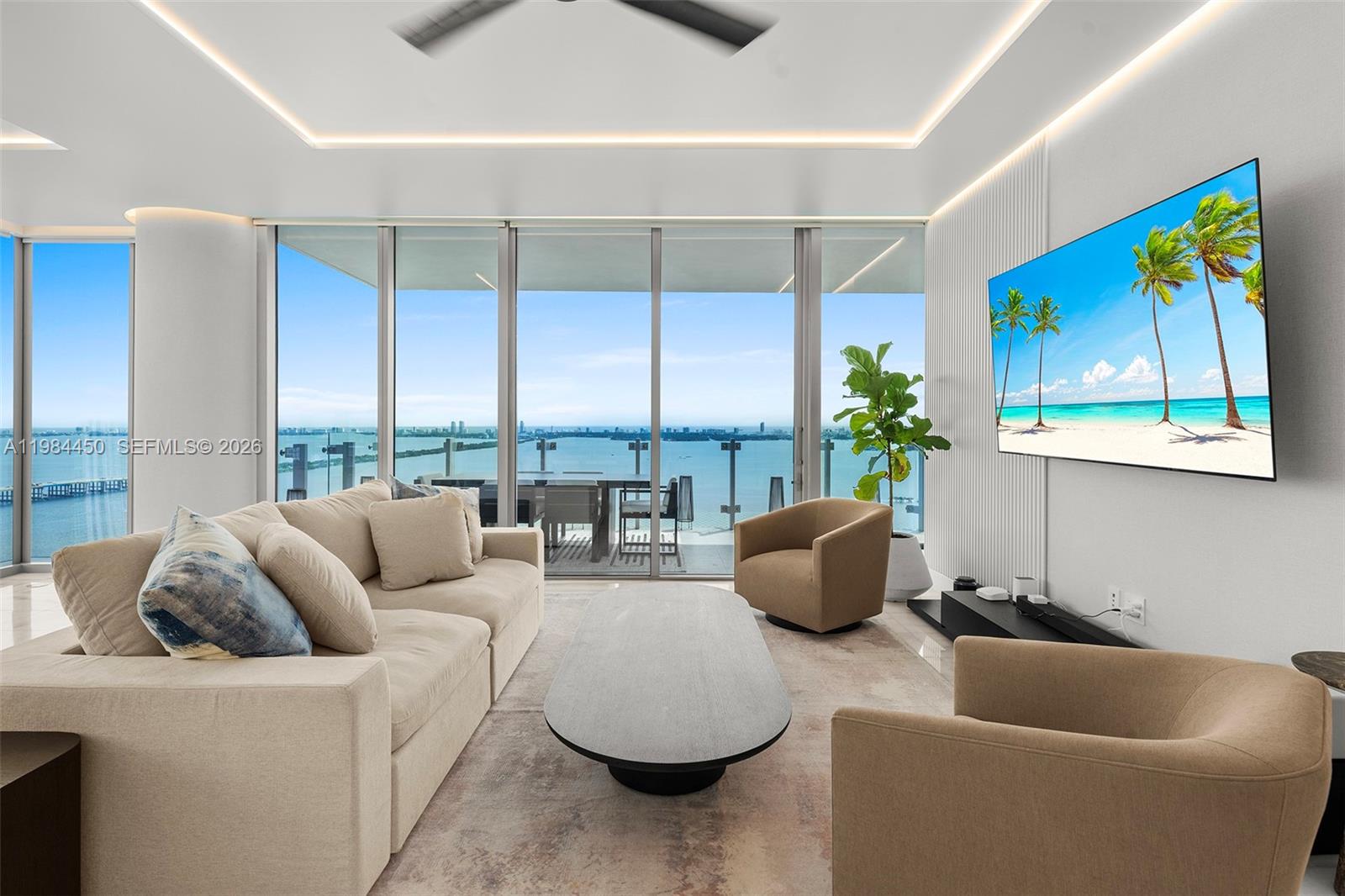 A modern living room features a beige sofa, two armchairs, and floor-to-ceiling windows overlooking water — 700 NE 26th Ter # 3401, Miami FL 33137, MIAMI, FL