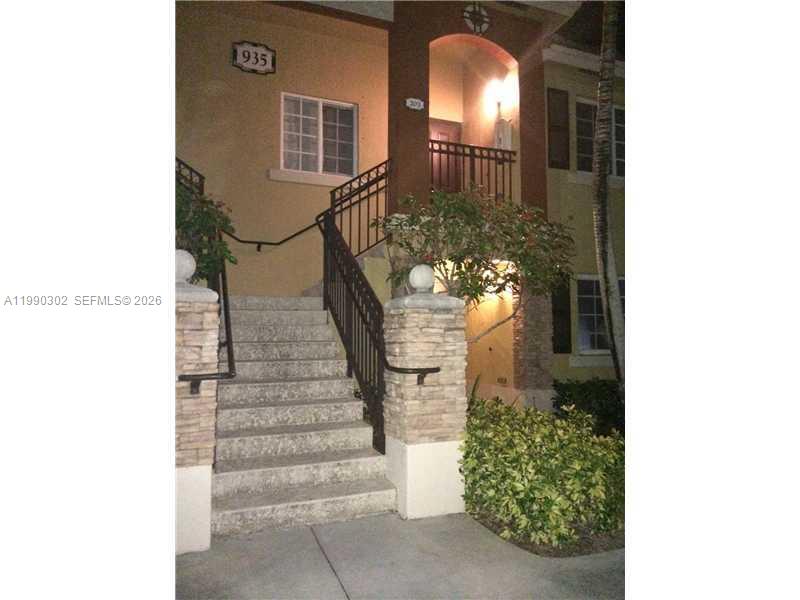An exterior view shows a concrete staircase leading to a second-story entrance with stone pillars — 935 NE 33rd Ter # 203, Homestead FL 33033, HOMESTEAD, FL