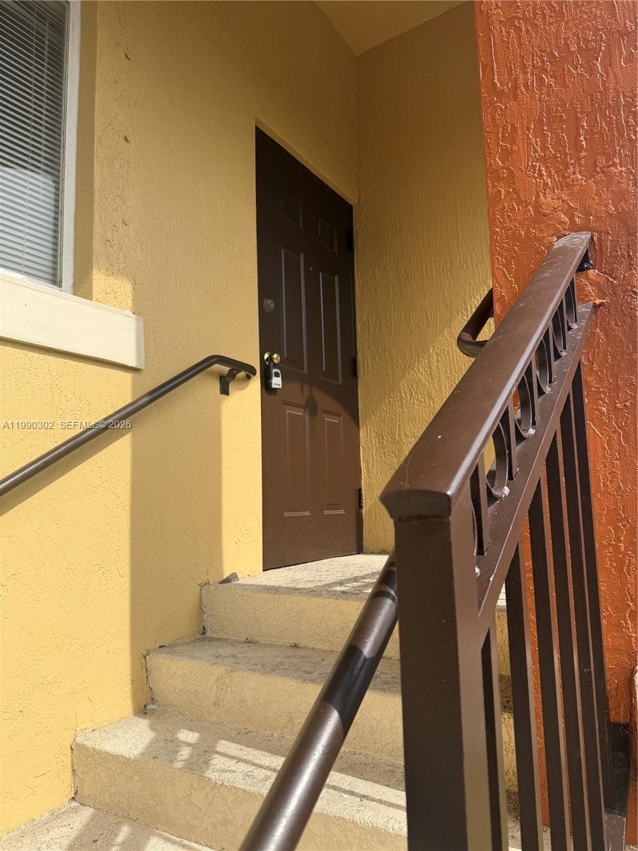 A brown door is at the top of concrete stairs with metal railings — 935 NE 33rd Ter # 203, Homestead FL 33033, HOMESTEAD, FL