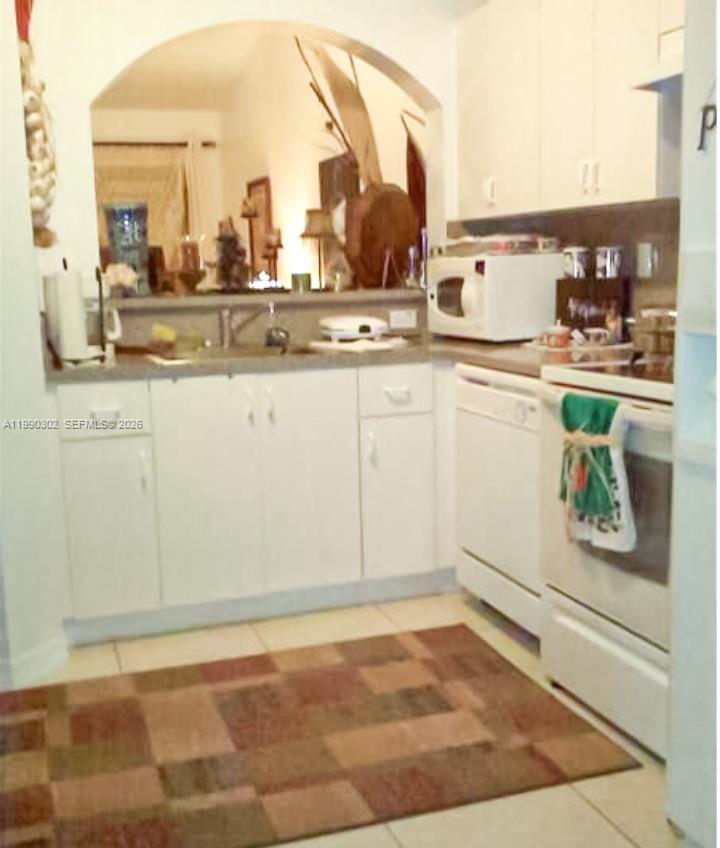 A kitchen features white cabinets, a white dishwasher, a microwave, and a patterned area rug — 935 NE 33rd Ter # 203, Homestead FL 33033, HOMESTEAD, FL