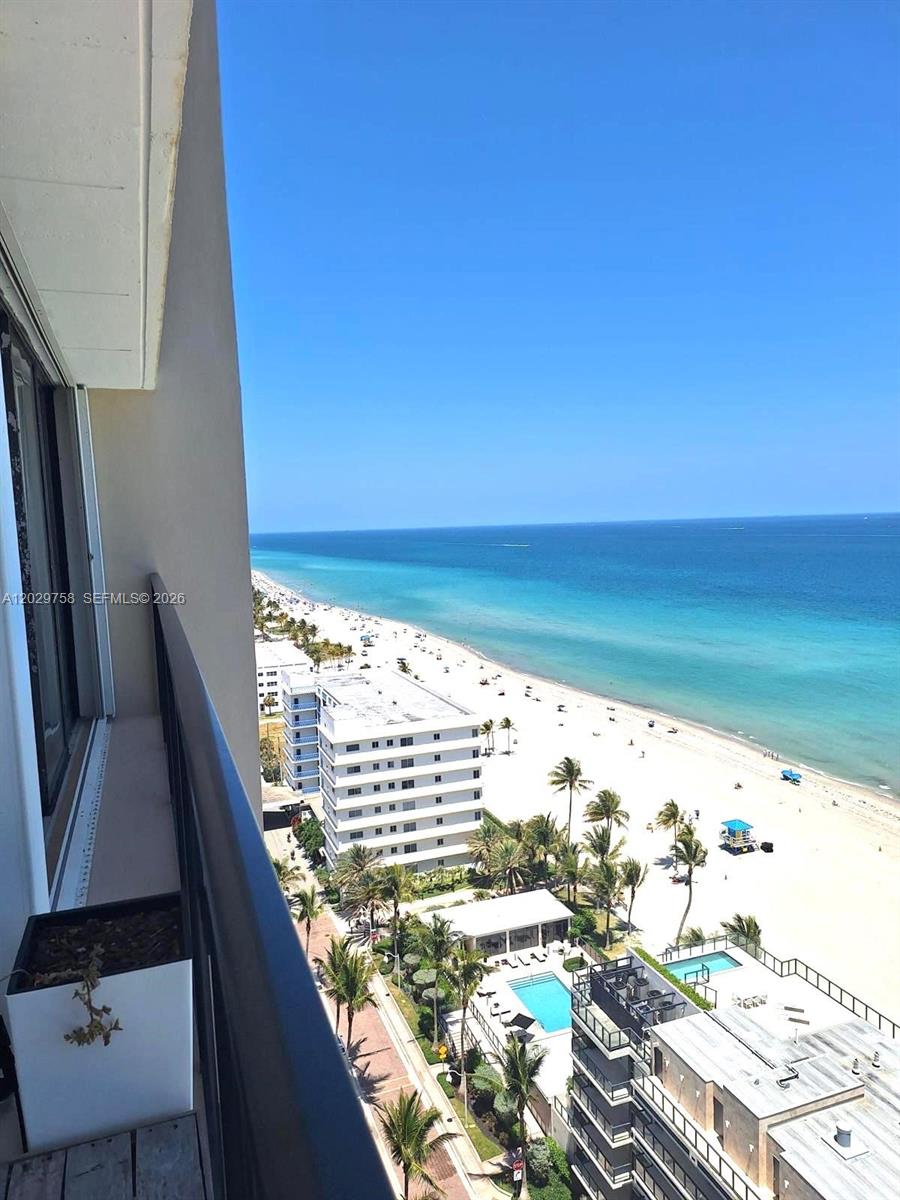 A high-angle view from a balcony overlooking a beach, ocean, and nearby buildings — 2201 S Ocean Dr # 2001, Hollywood FL 33019, HOLLYWOOD, FL