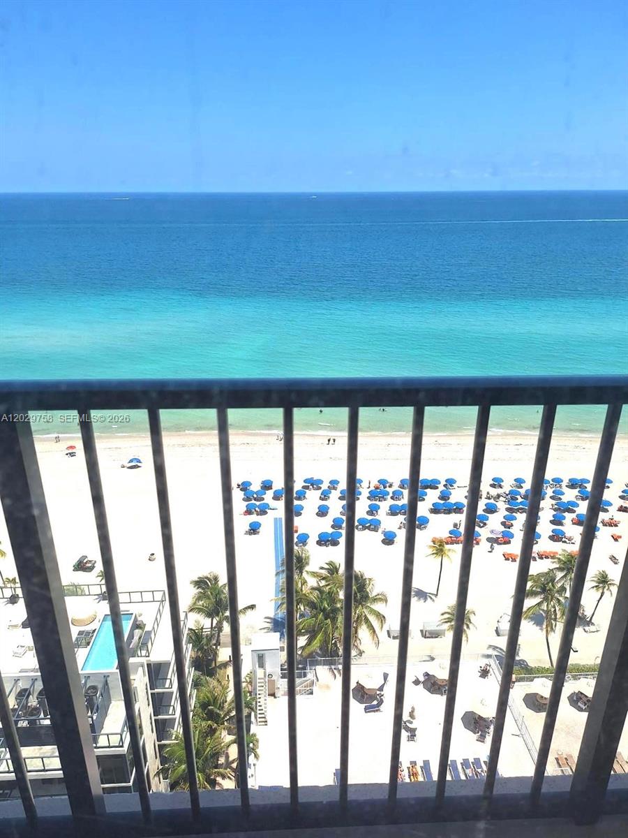 A high-angle view from a balcony overlooking a beach with blue umbrellas and ocean — 2201 S Ocean Dr # 2001, Hollywood FL 33019, HOLLYWOOD, FL