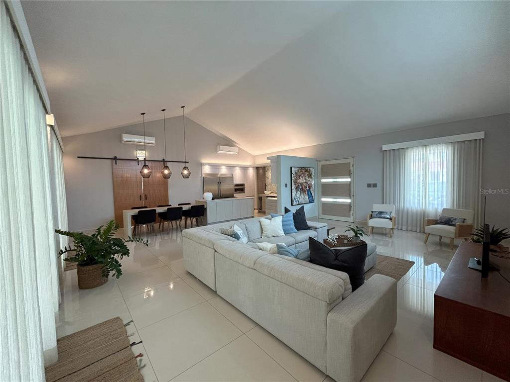A spacious open-concept living and dining area features vaulted ceilings, tile floors, and modern furniture — 312 SABANERA DORADO, DORADO, PR