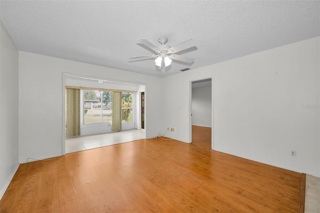 A living room with wood-look flooring, a ceiling fan, and an adjacent sunroom — 3819 TEESIDE DRIVE, NEW PORT RICHEY, FL