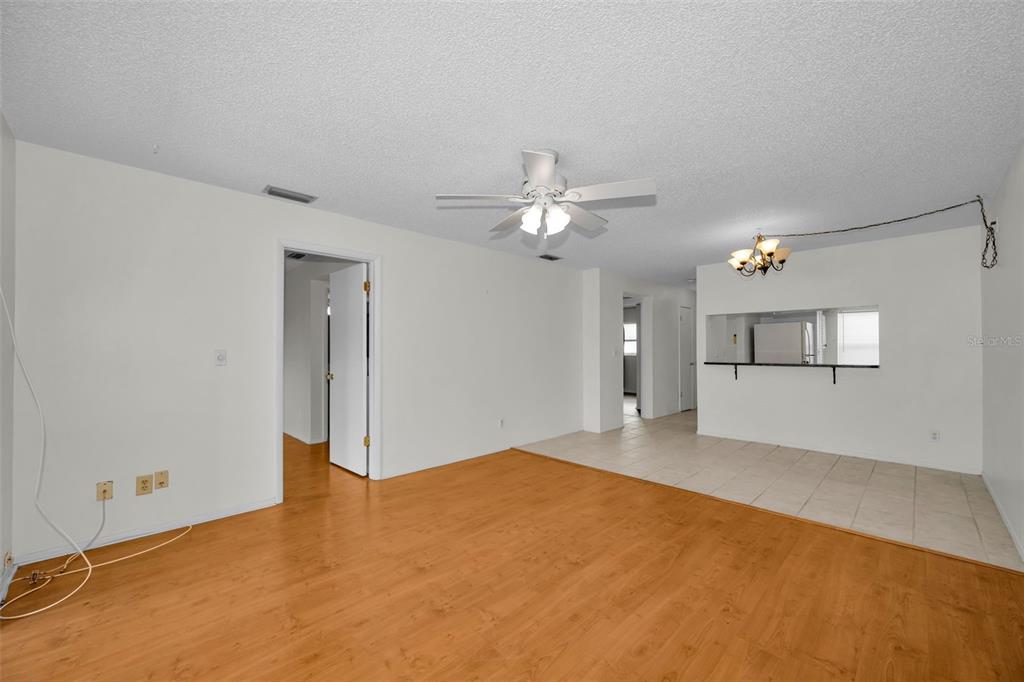 An open living area features wood-look flooring, a ceiling fan, and a tiled dining space — 3819 TEESIDE DRIVE, NEW PORT RICHEY, FL