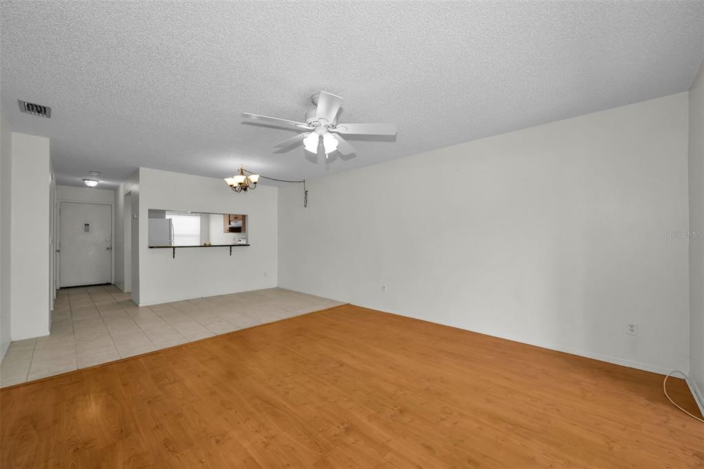 An open living room features light wood-look flooring, a ceiling fan, and a tiled entryway — 3819 TEESIDE DRIVE, NEW PORT RICHEY, FL