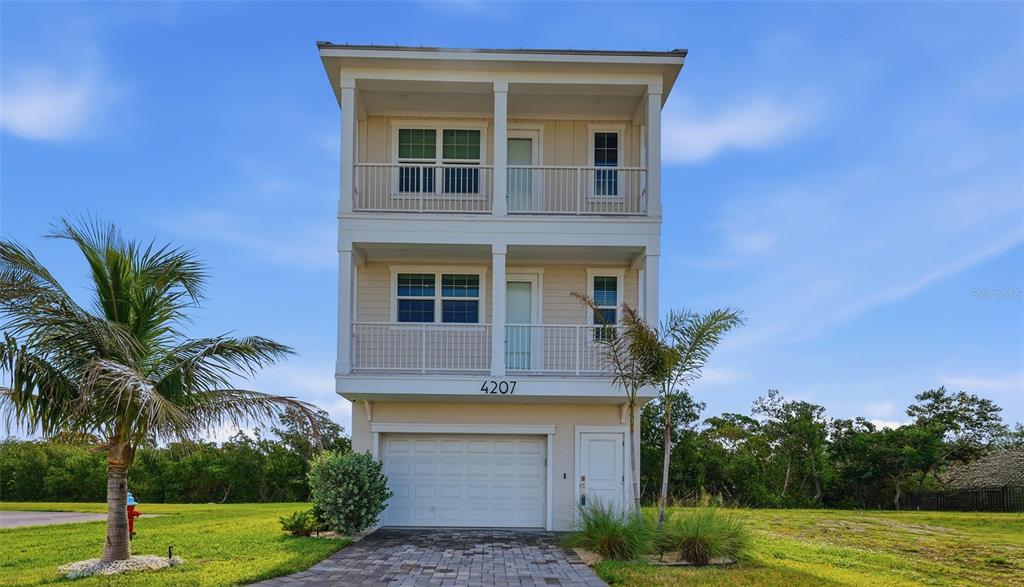 A three-story house features a ground-level garage, two stacked balconies, and a paved driveway — 4207 MARINA VIEW WAY, CORTEZ, FL