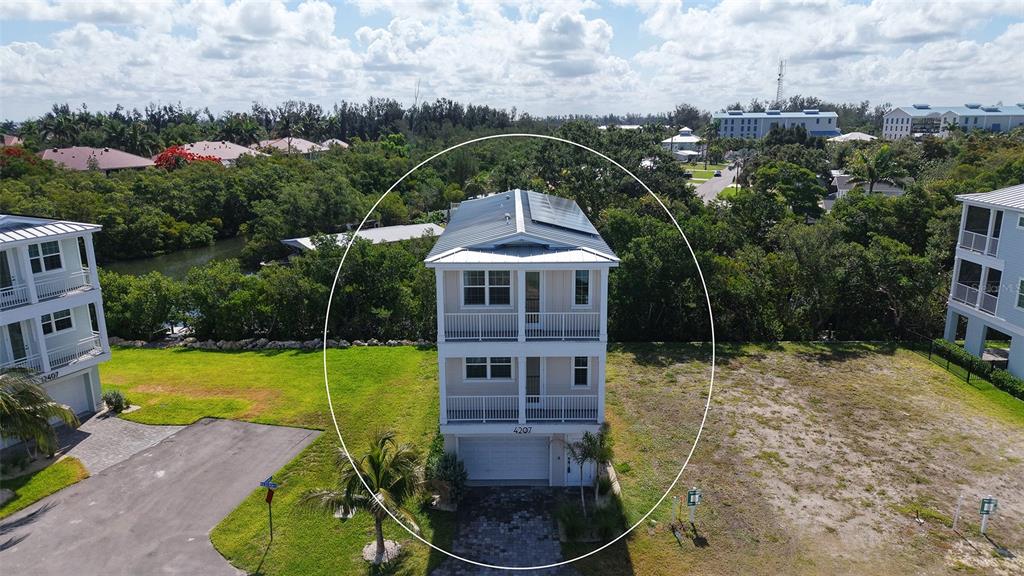 An aerial view shows a three-story house with a garage and balconies surrounded by trees — 4207 MARINA VIEW WAY, CORTEZ, FL