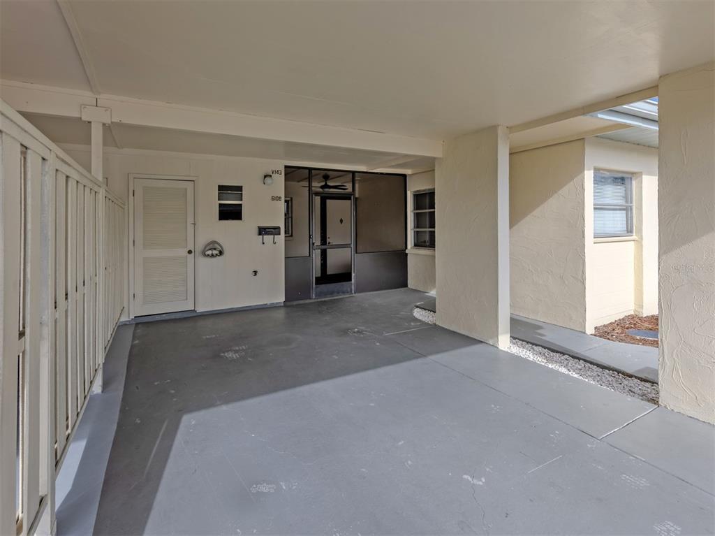 A covered carport area features a concrete floor, a white door, and a screened entrance — 6108 GREEN VIEW DRIVE UNIT 143, SARASOTA, FL