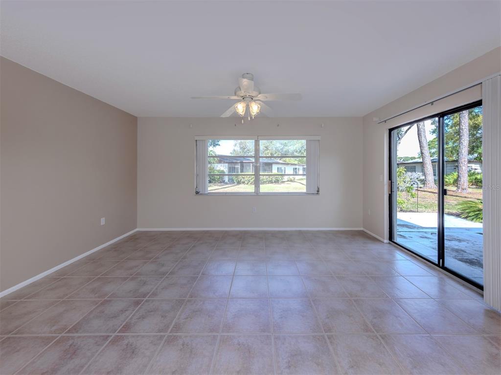 An empty room with beige walls, tile flooring, a ceiling fan, and a sliding glass door — 6108 GREEN VIEW DRIVE UNIT 143, SARASOTA, FL