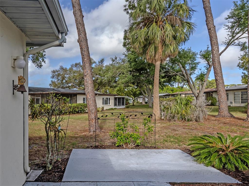 A concrete patio overlooks a grassy backyard with trees and neighboring houses — 6108 GREEN VIEW DRIVE UNIT 143, SARASOTA, FL