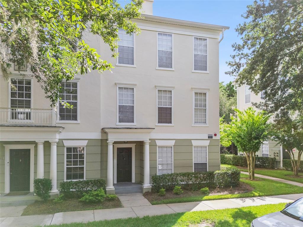 A three-story townhouse with a light-colored exterior, green lower siding, and a covered front entrance — 310 GRAND MAGNOLIA AVENUE UNIT 310, CELEBRATION, FL