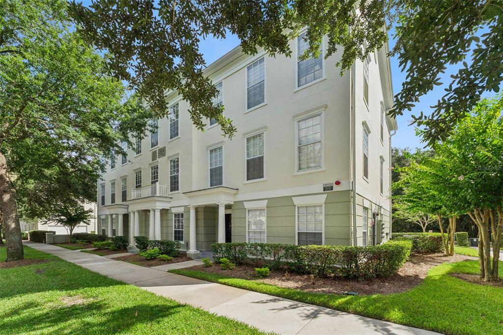 A three-story apartment building with a light-colored facade, white columns, and surrounding landscaping — 310 GRAND MAGNOLIA AVENUE UNIT 310, CELEBRATION, FL
