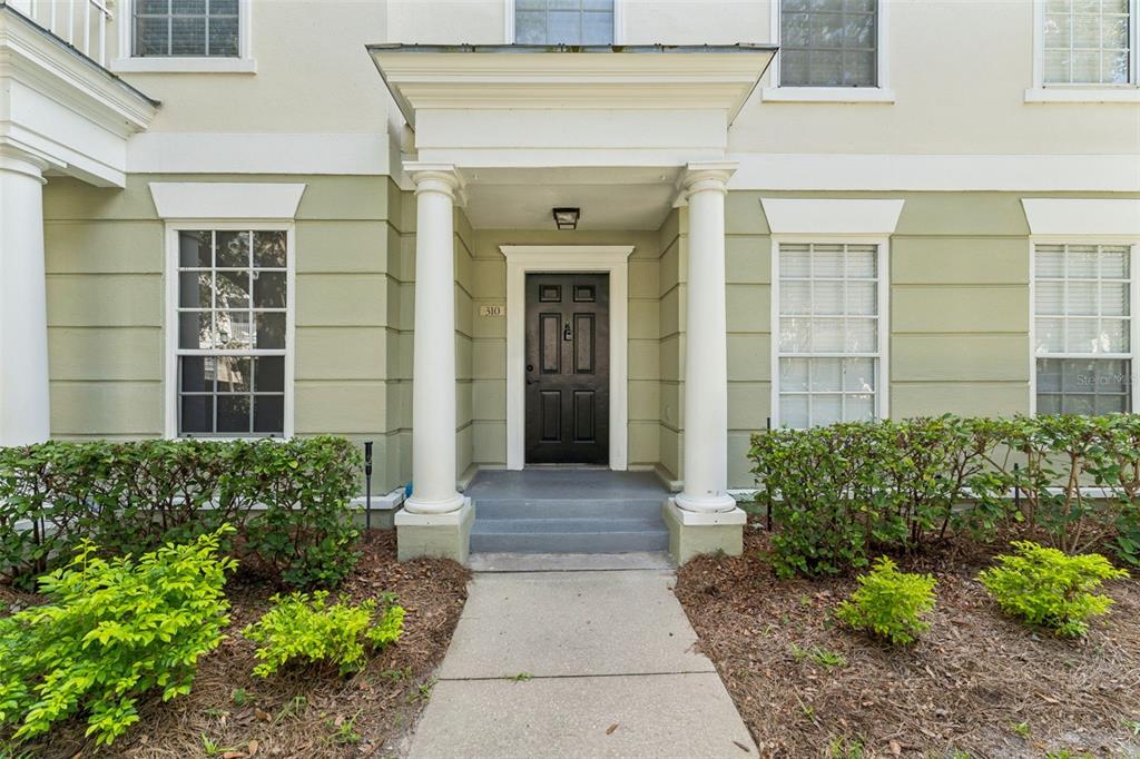 A black front door with a portico and two white columns stands at the entrance — 310 GRAND MAGNOLIA AVENUE UNIT 310, CELEBRATION, FL