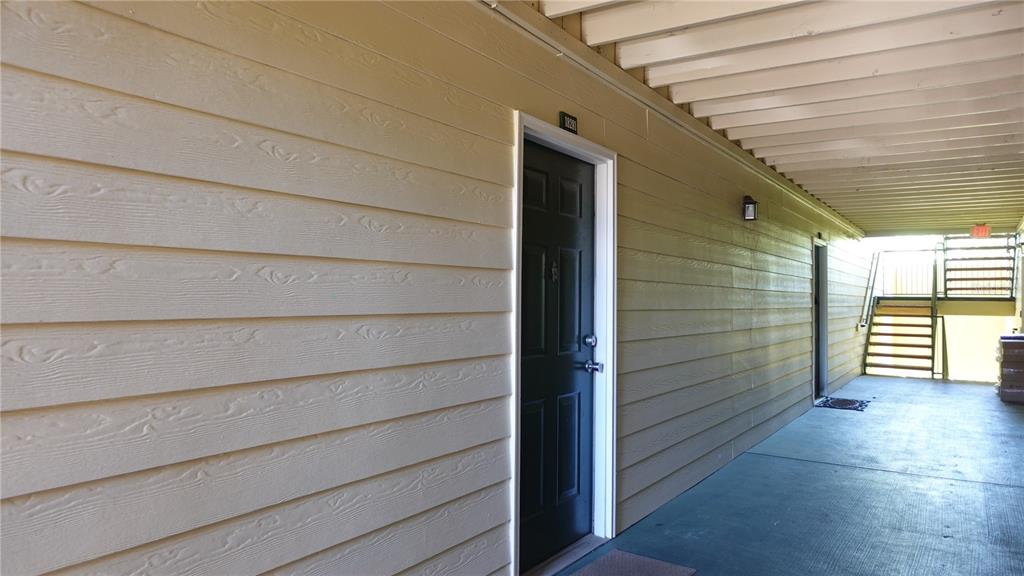A tan-sided apartment building exterior features a black front door and an outdoor walkway — 18281 BRIDLE CLUB DRIVE, TAMPA, FL