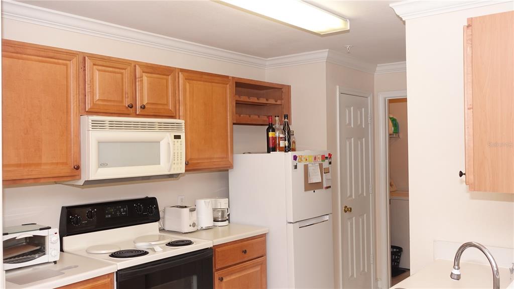 A kitchen features light wood cabinets, white appliances, and a white countertop — 18281 BRIDLE CLUB DRIVE, TAMPA, FL