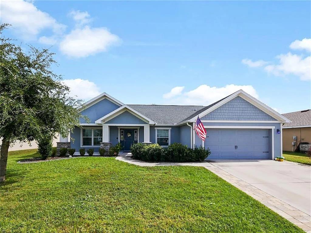 A blue single-story house with a two-car garage and a front yard under a sky — 218 CATTAIL WAY, LAKE ALFRED, FL