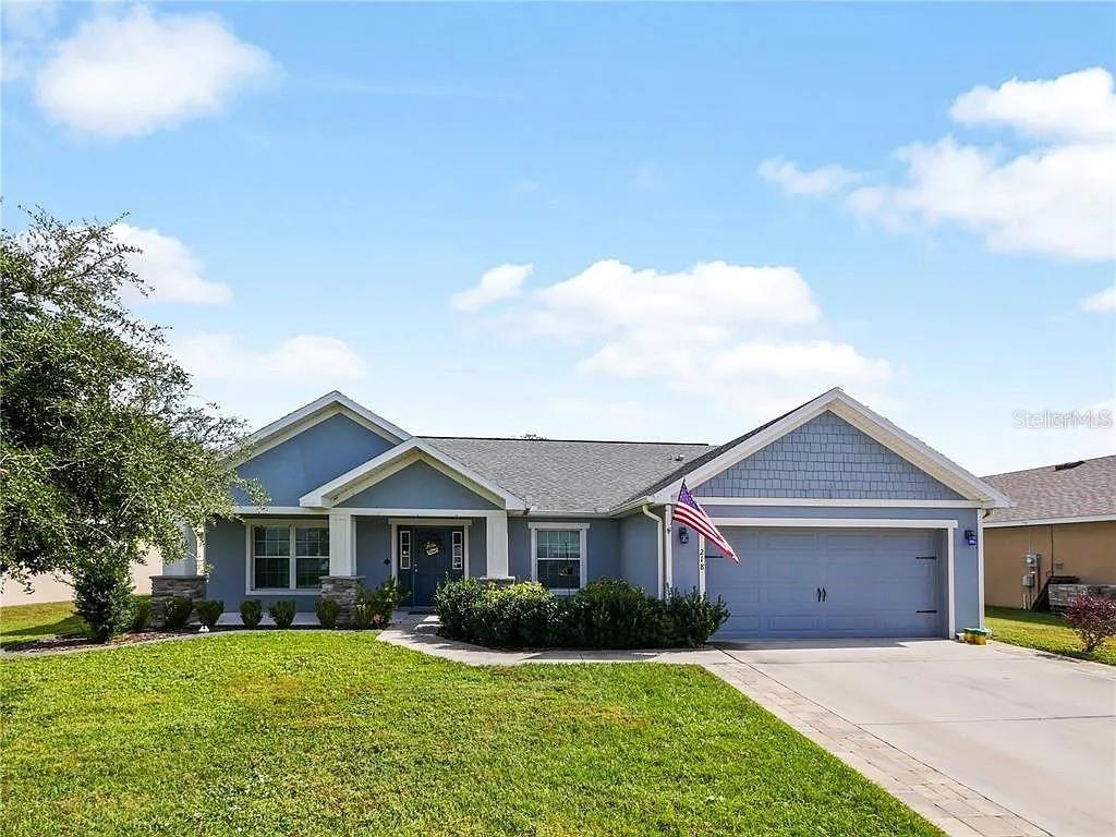 A blue single-story house with a two-car garage and a front lawn under a sky — 218 CATTAIL WAY, LAKE ALFRED, FL