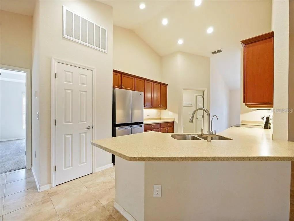 A kitchen with light countertops, wood cabinets, stainless steel appliances, and a vaulted ceiling — 218 CATTAIL WAY, LAKE ALFRED, FL