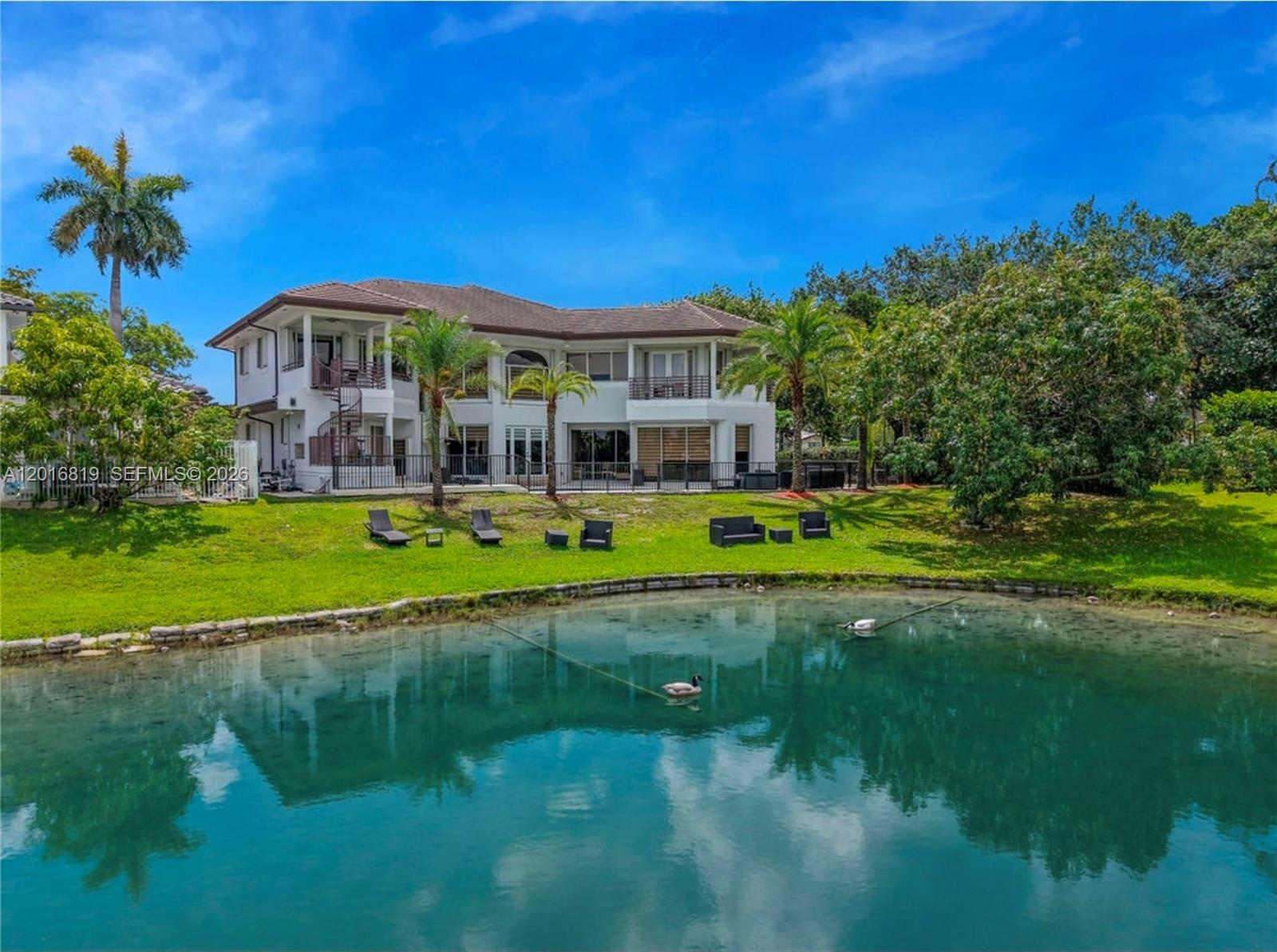 A two-story house with a spiral staircase overlooks a pond and a grassy backyard — 14332 Ardoch Pl, Miami Lakes FL 33016, MIAMI LAKES, FL