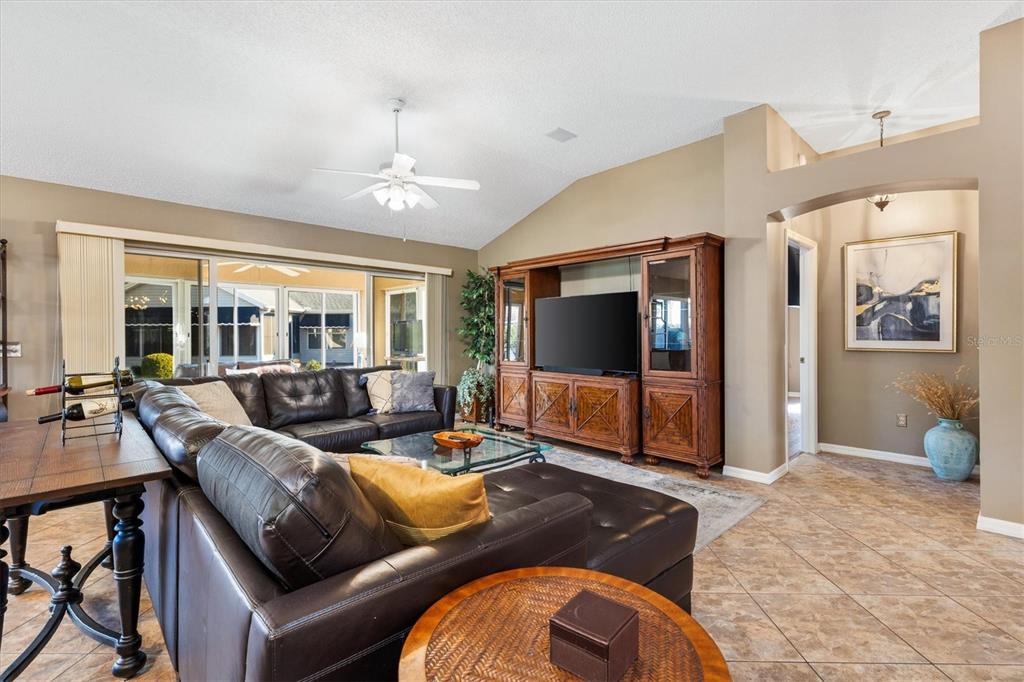 A living room features a dark leather sectional, a large wooden entertainment center, and tile flooring — 1505 DORIA LANE, LADY LAKE, FL