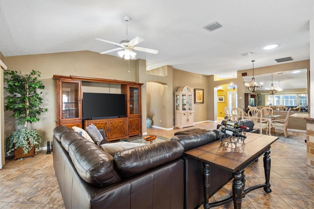 A living room features a leather sectional, a large wooden entertainment center, and tile flooring — 1505 DORIA LANE, LADY LAKE, FL