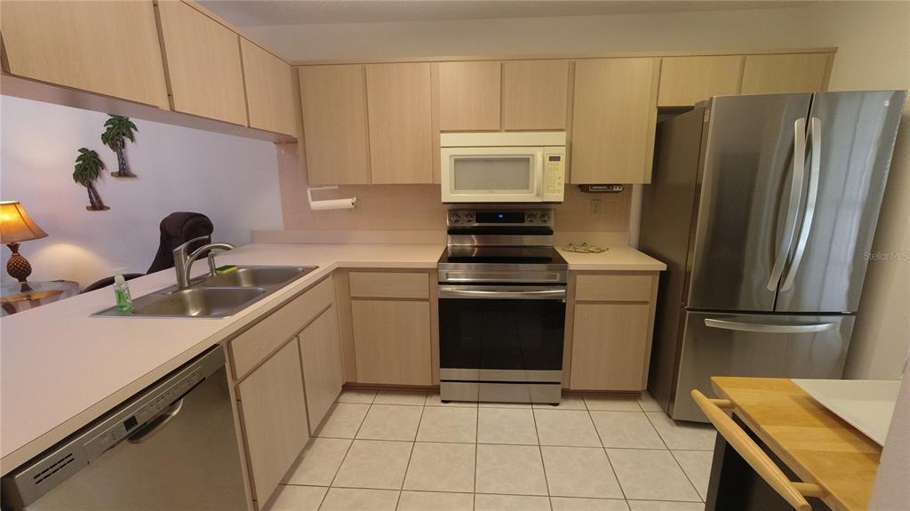 A kitchen features light wood cabinets, stainless steel appliances, and a tiled floor — 6421 REMUS DRIVE, NEW PORT RICHEY, FL