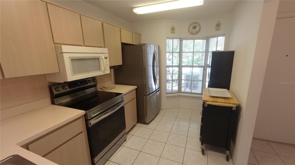 A kitchen features light wood cabinets, stainless steel appliances, and a windowed breakfast nook — 6421 REMUS DRIVE, NEW PORT RICHEY, FL