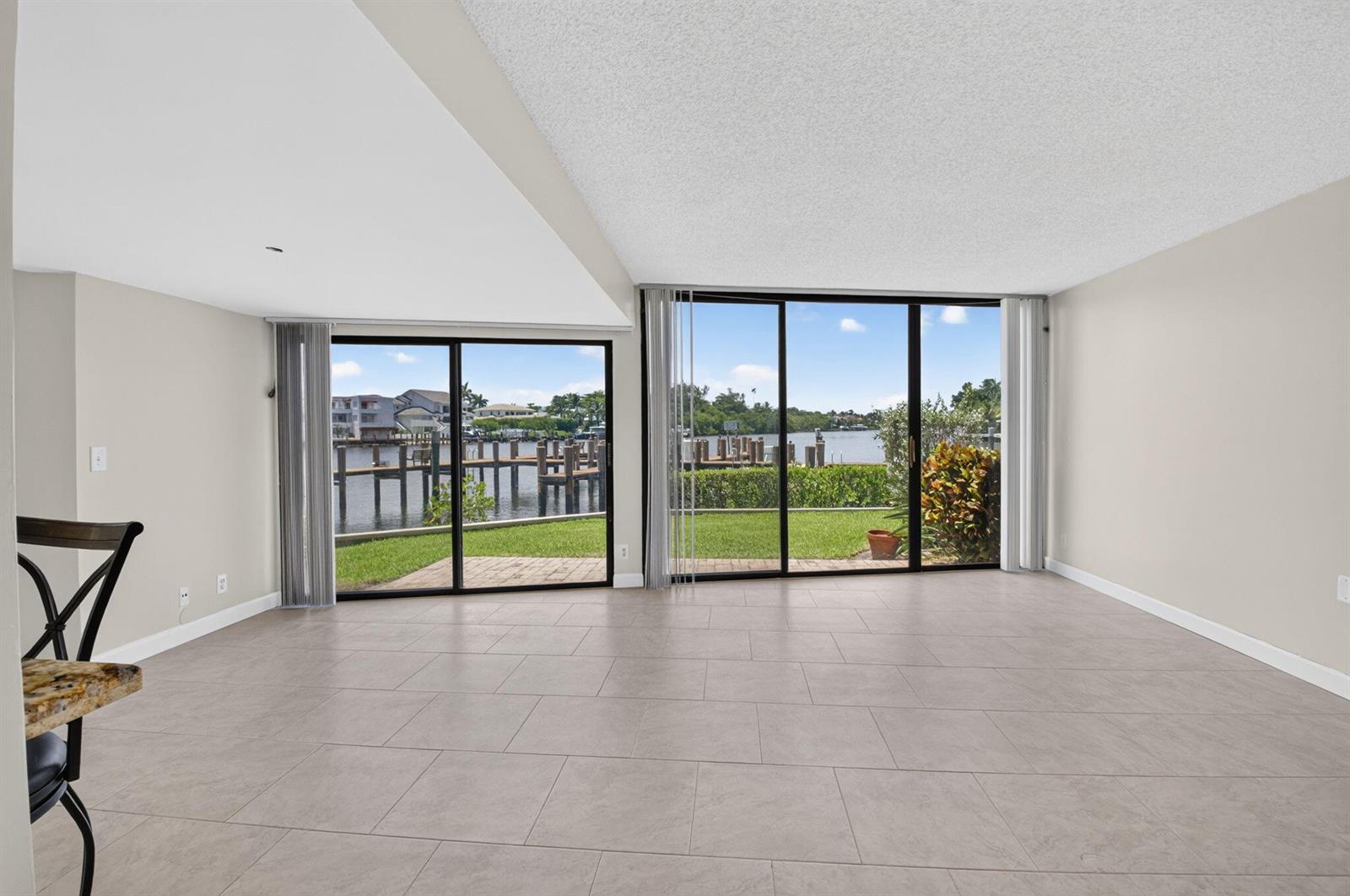 An empty living room with large sliding glass doors overlooking a canal and boat docks — 1111 George Bush Boulevard # A, Delray Beach FL 33483, DELRAY BEACH, FL