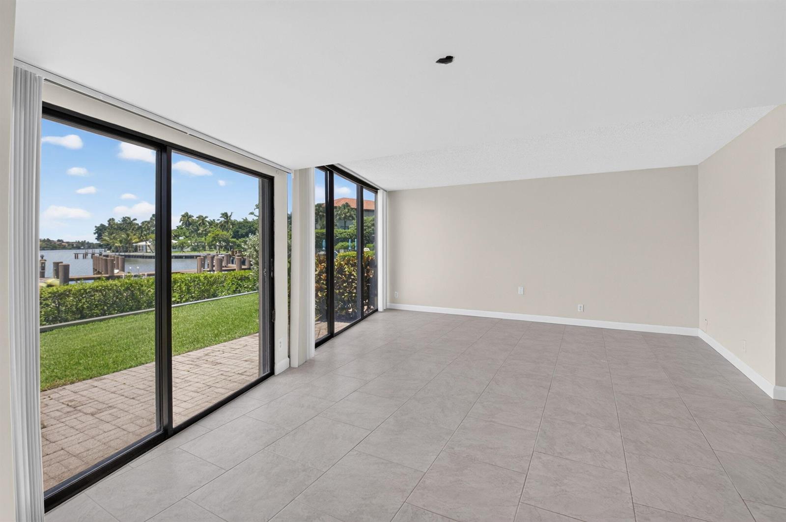 An empty room with large sliding glass doors, tile flooring, and a view of water — 1111 George Bush Boulevard # A, Delray Beach FL 33483, DELRAY BEACH, FL