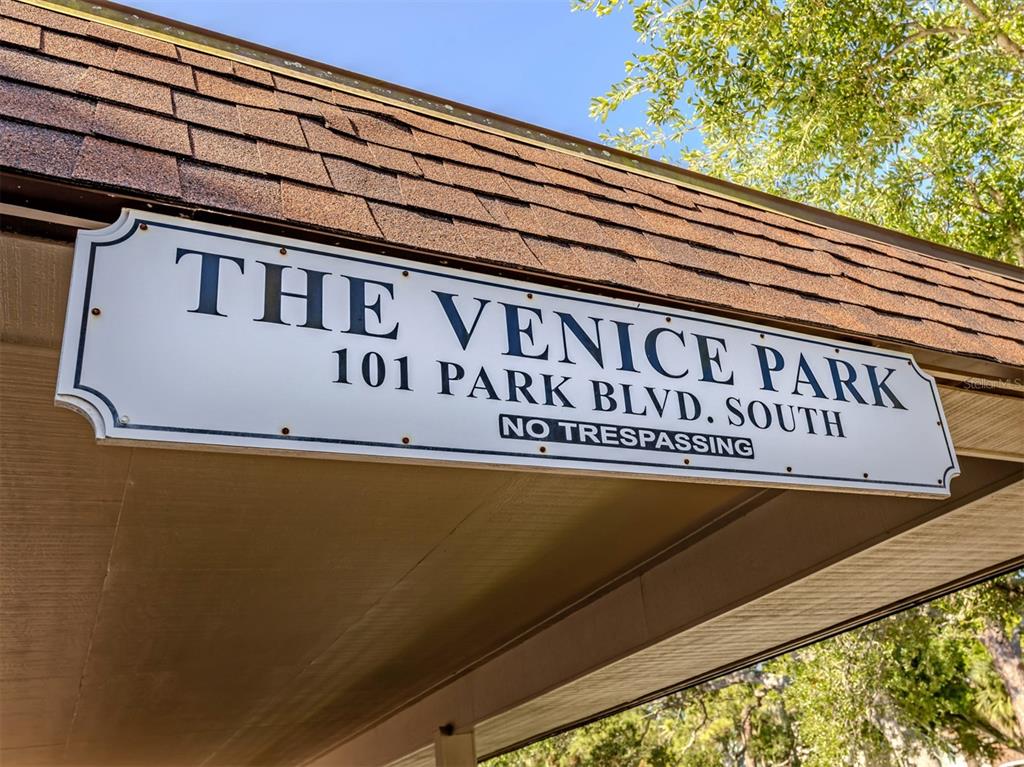 A beige exterior wall features a white door, two windows, and a tiled patio floor — 101 PARK BOULEVARD S UNIT 106, VENICE, FL