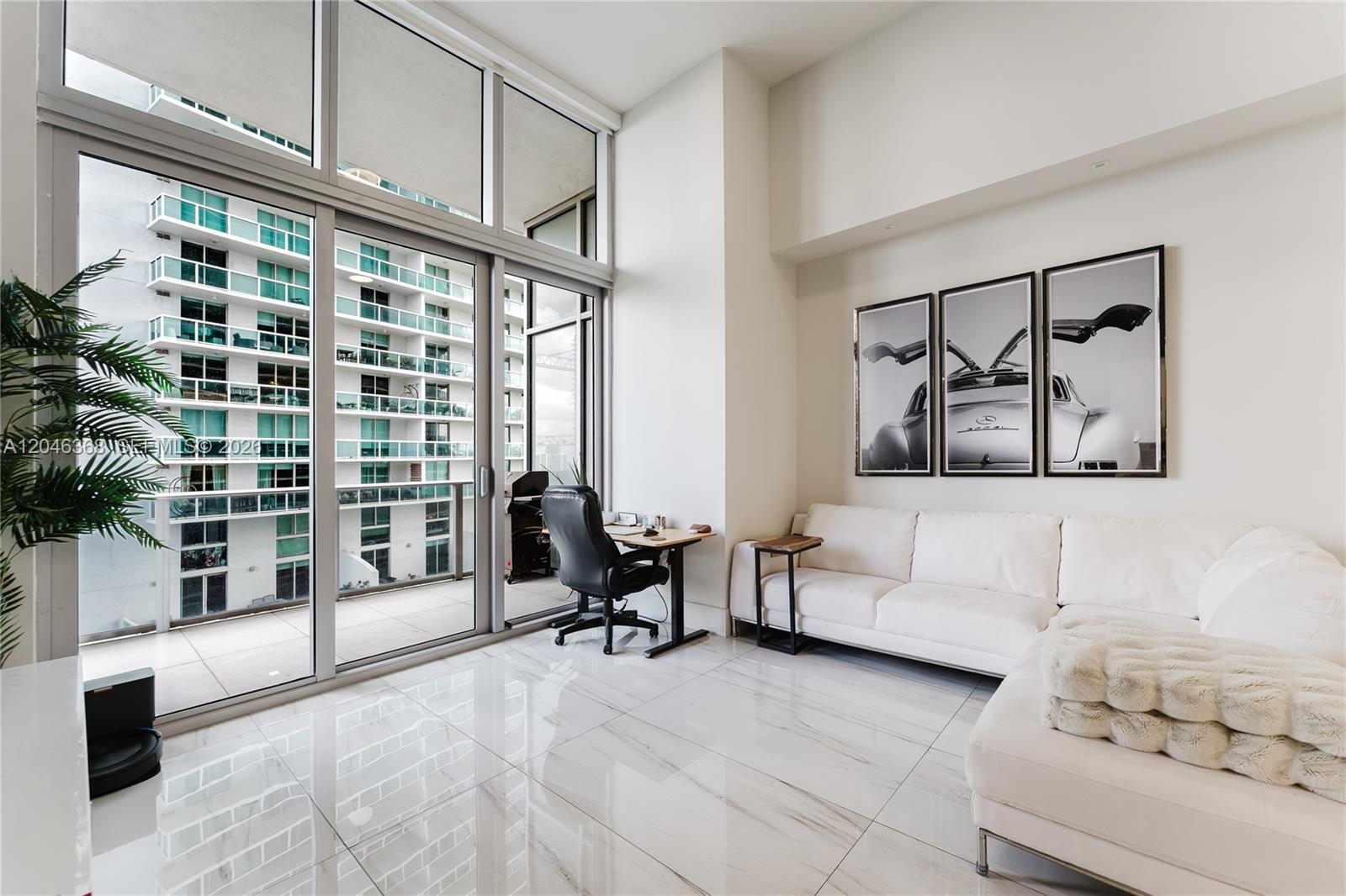 A modern living room features white tile floors, a sectional sofa, and floor-to-ceiling windows — 488 NE 18th St # 1205, Miami FL 33132, MIAMI, FL