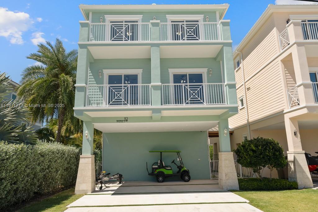 A three-story light green house features two stacked balconies and a covered ground-level parking area — 112 Avenue D # 1, Marathon FL 33050, MARATHON, FL