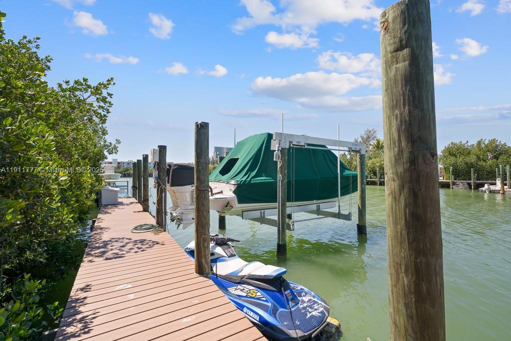 A wooden dock extends into the water, featuring a boat on a lift and a jet ski — 112 Avenue D # 1, Marathon FL 33050, MARATHON, FL