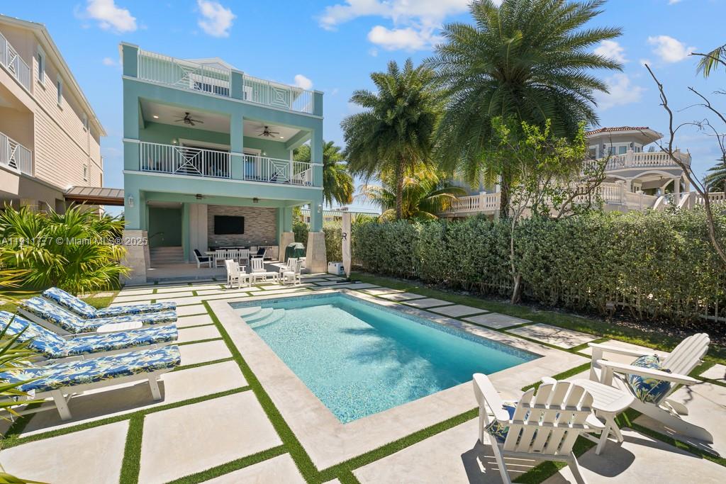 A multi-story teal house features a swimming pool, patio furniture, and a landscaped backyard — 112 Avenue D # 1, Marathon FL 33050, MARATHON, FL